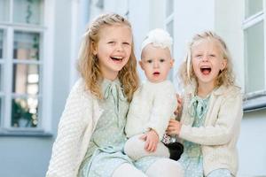 3 kleine Mädchen mit hellem Haar umarmen sich. Liebe der Schwestern foto