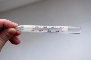 Quecksilberthermometer mit einer Temperatur von 39 in den Händen auf weißem Hintergrund foto