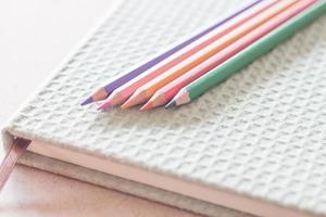 Nahaufnahme von bunten Stiften auf einem grünen Notizbuch foto
