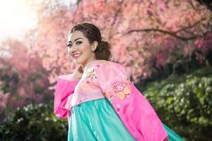 hanbok, das traditionelle koreanische kleid und das schöne asiatische mädchen mit sakura foto