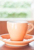 orange Tasse Kaffee in der Nähe eines Fensters foto