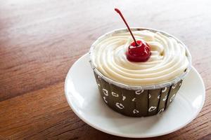 Cupcake mit roter Kirsche auf einem weißen Teller