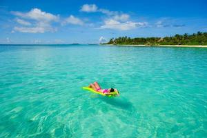 Frau, die auf Floaty am Strand entspannt foto