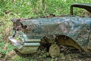 Altes verrostetes Auto, das im Wald mit Einschusslöchern aufgegeben wurde foto