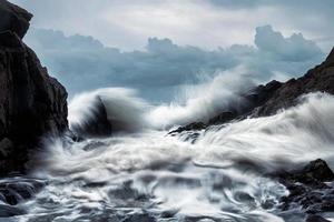 große Welle trifft die Felsen im Sturm foto