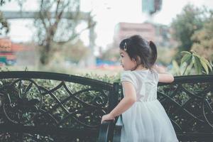 süßes, glückliches, lächelndes dreijähriges Mädchen, das in einem Park im Freien spielt foto