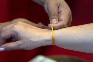 tibetischer Mönch beim Anlegen des Armbands an der buddhistischen Hand foto