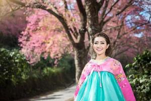 hanbok, das traditionelle koreanische kleid und das schöne asiatische mädchen mit sakura foto