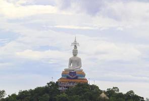weißes buddha-bild auf einem hohen berg, erbaut mit dem glauben des buddhismus als spiritueller anker und umgeben von grünen bäumen, schärft die hohen berge. foto
