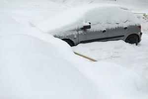 Auto im Winter auf dem Parkplatz. Auto ist im Schnee geparkt. Schneeverwehungen auf dem Parkplatz. foto