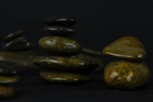 Schichten von dunklen Steinen auf schwarzem Hintergrund, die für entspannende Konzepte wie Yoga, Massage und Peace Space Stones Konzept des Tapetendesigns verwendet werden. foto