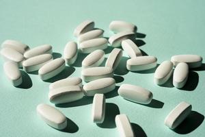 tabletten, vitamine auf türkisfarbenem hintergrund, ein minimalistisches konzept foto