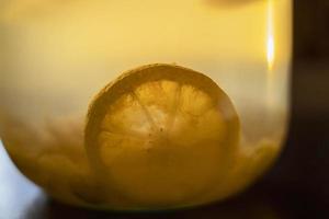Zitronenscheibe in Apfelkompott in einem Glas auf dem Tisch, sanftes Abendlicht foto