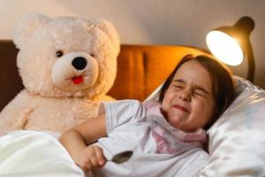 kleines Mädchen mit Krankheit auf dem Bett foto