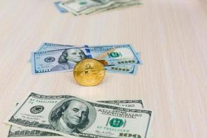 Eine symbolische Bitcoin-Münze auf Banknoten von hundert Dollar tauscht Bitcoin-Bargeld gegen einen Dollar foto
