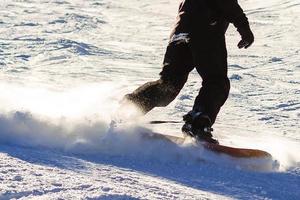 Snowboarder, der eine Zehenseitenschnitzerei mit tiefblauem Himmel im Hintergrund tut foto