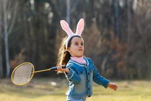 kleines Mädchen, das Badminton auf der Wiese spielt foto