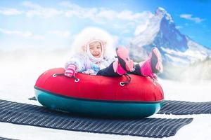 kleines Mädchen mit Snowtube bereit zum Rodeln einen Hügel hinunter foto