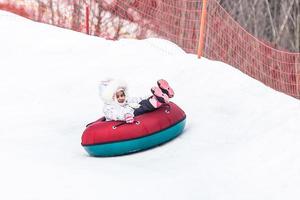 kleines Mädchen mit Snowtube bereit zum Rodeln einen Hügel hinunter foto