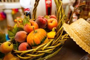 Korb mit Pfirsichen und Birnen Reifer gelber Kürbis unter Herbstlaub auf einer Fensterbank foto