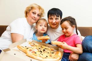 familie, die zu hause zusammen pizza isst foto