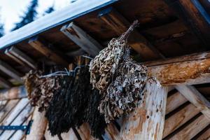 Die Birkenbesen für ein traditionelles Dampfbad hängen unter dem Dach des Holzhauses foto