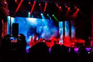 Aufnahme einiger jubelnder Fans während eines Live-Konzerts, sichtbares Rauschen durch hohe ISO, weicher Fokus, flacher DOF, leichte Bewegungsunschärfe foto