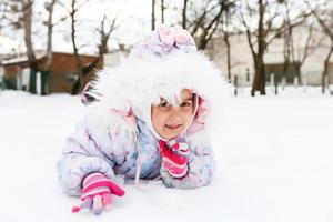 Porträt eines kleinen Mädchens, das im Schnee lächelt foto