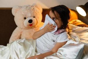 Hochwinkelporträt eines süßen kleinen Mädchens, das unter Kälte leidet, während sie im Bett liegt foto