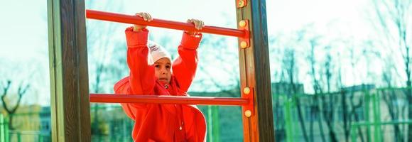 Porträt eines glücklichen kleinen Mädchens, das auf einem Seilnetzspielplatz im Freien spielt foto