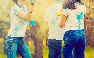 Fröhliche Freunde, die im Sommer beim Holi-Festival mit bunter Pulverwolke feiern - junge Leute, die sich auf der Strandparty amüsieren - Jugend- und Freundschaftskonzept - Fokus auf das Gesicht der mittleren Mädchen - warmer Filter foto