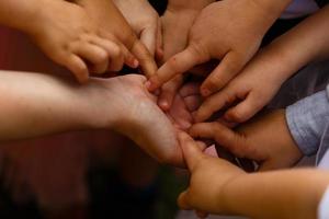 Nahaufnahme vieler Kinderhände, die als Team auf einem Naturhintergrund zusammenhalten foto