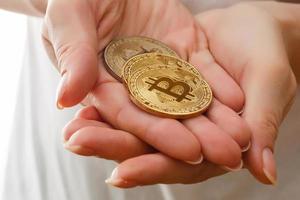 Zwei goldene Bitcoins in der Hand digitales Symbol einer neuen virtuellen Währung isoliert auf Weiß foto
