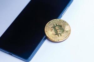 ein bitcoin und ein smartphone auf einer weißen isolierten oberfläche foto