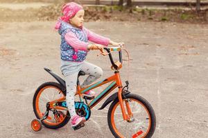 Kinder, die draußen auf einer Einfahrt Fahrrad fahren lernen. kleine mädchen, die fahrräder auf asphaltierten straßen in der stadt fahren foto