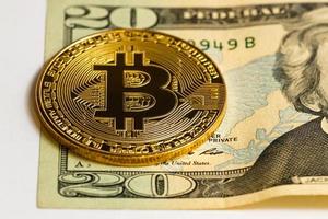 Gold-Bitcoin auf weißem Hintergrund neben uns Papiergeld mit einem Nennwert von Dollar foto