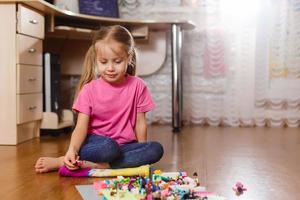 kleines Mädchen spielt mit Spielzeugdesigner und Würfeln foto