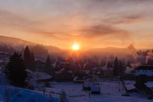 Bunter Herbstmorgen in den Karpaten. Dramatischer Sonnenaufgang im Bergdorf. nachbearbeitetes Foto im künstlerischen Stil.