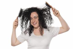 junge Frau, die versucht, ihr lockiges Haar zu kämmen foto