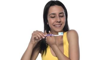 glückliche junge Frau mit gesunden Zähnen, die eine Zahnbürste hält foto