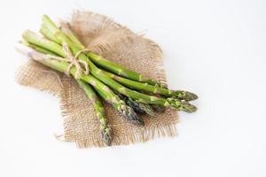 frischer grüner Spargel mit Faden gebunden und auf Sackleinen liegend. gesundes und gesundes lebensmittelkonzept. von oben betrachten. foto