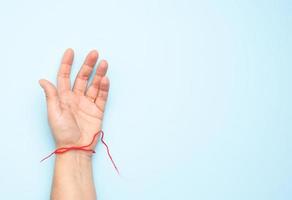 roter Wollfaden am Handgelenk einer weiblichen Hand foto