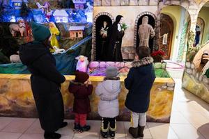 mutter mit drei kindern besuchen die weihnachtskrippe in der kirche. foto