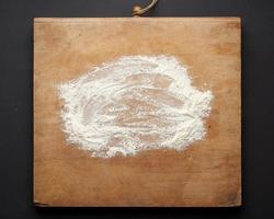 weißes Weizenmehl auf einem Holztisch verstreut foto