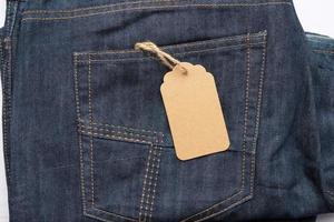 leeres braunes rechteckiges Etikett, das in der Gesäßtasche einer blauen gefalteten Jeans gebunden ist foto