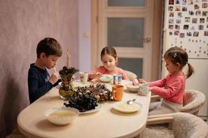 Drei Kinder essen zusammen in der Küche zu Abend. foto