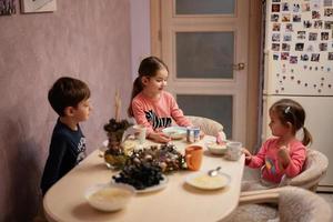 Drei Kinder essen zusammen in der Küche zu Abend. foto