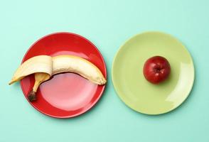 roter reifer Apfel und Banane liegen in einer runden Keramikplatte foto