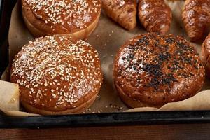 Gebackene Sesambrötchen auf braunem Pergamentpapier, Zutat für einen Hamburger foto