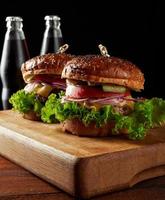 leckerer Burger mit gebratenem Rinderkotelett und Zwiebeln. knuspriges Weißmehlbrötchen mit Sesam. Fast Food auf einem Holzbrett foto